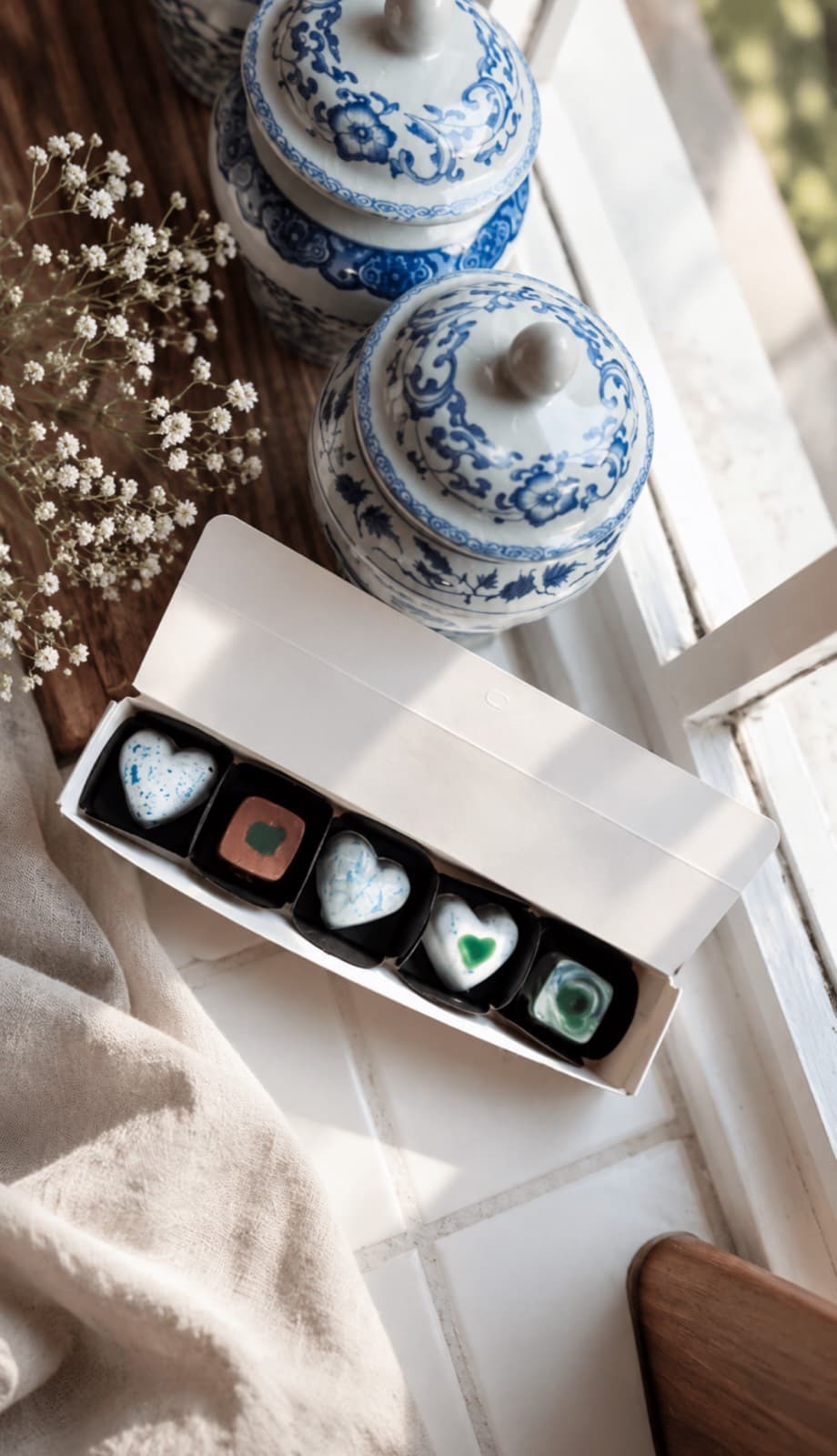 Pralines in a sleeve box beside blue porcelain jars